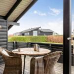 Terrasse mit Tisch und Stühlen, Blick auf grüne Hecke und Ferienhäuser.