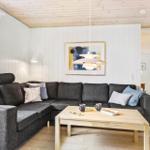 Ein Wohnzimmer mit grauem Sofa, Holztisch und weißen Wänden.