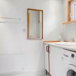 Badezimmer mit Waschmaschine, Spüle und Spiegel an der Wand.