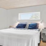 Schlafzimmer mit weißer Wand und Bett mit blauen Kissen.
