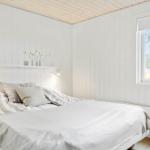 Schlafzimmer mit Bett, Fenster und weißen Wänden.