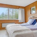 Schlafzimmer mit Holzwand, großem Fenster und Stuhl.