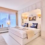 Schlafzimmer mit großem Bett, weißen Schränken und Fenster mit Blick.