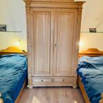 Zwei Betten mit blauen Bettdecken und ein Holzschrank in einem Schlafzimmer.