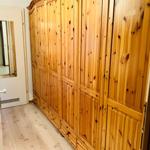 Großer Holzschrank mit mehreren Türen und Schubladen in einem Raum mit Holzboden.