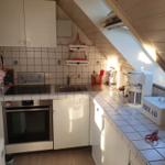 Küche mit Spüle, Herd und Backofen unter Dachschräge.