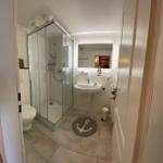 Badezimmer mit Dusche, Waschbecken und Toilette. Bodenmatte mit Ankermotiv.