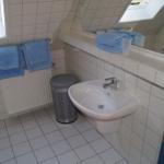 Badezimmer mit Waschbecken, Spiegel, Handtüchern und Fenster.