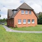 Rotes Backsteingebäude mit Dachgauben und Rasenfläche.