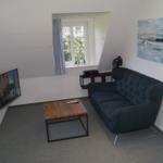 Ein Wohnzimmer mit Sofa, Couchtisch und Fernseher an der Wand.
