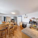 Küche mit Essbereich, Holztisch, Stühle, Spüle und Kochgeräte.