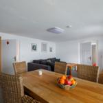 Esszimmer mit Esstisch, Stühlen und Sofa im Hintergrund.