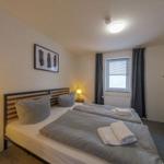 Schlafzimmer mit Doppelbett, Nachttisch, Kleiderschrank und Fenster mit Vorhängen.