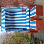 Ein blau-weiß gestreifter Strandkorb mit Holzrahmen und Kette.