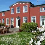 Rotes Haus mit Garten, Terrasse und Blumen. Außenbereich mit Tisch und Stühlen.