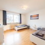 Zwei Betten, Fenster, Fernseher und Wandbild im Schlafzimmer.