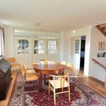 Esszimmer mit Holztisch, Stühlen und Teppich. Holzstufen führen nach oben.