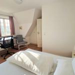 Schlafzimmer mit Bett, Schreibtisch und Fenster