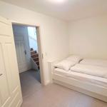 Schlafzimmer mit Doppelbett, Fenster und Tür zum Flur.