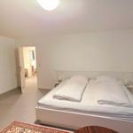 Schlafzimmer mit Doppelbett, Holzschrank und Blick in angrenzende Räume.