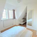 Schlafzimmer mit Dachschrägen, Fenster, Bett und Spiegel.