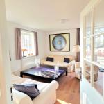 Wohnzimmer mit Sofa, Tisch und Fenster. Durchgangstür führt zum Garten.