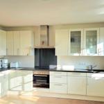 Küche mit weißen Schränken, dunklem Arbeitsplatz und integriertem Ofen.