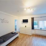 Schlafzimmer mit Bett, Schrank und Fenster mit Vorhängen.