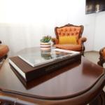 Lounge with three leather chairs, wooden table, and books.