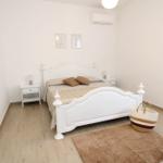 Bedroom with white bed, two nightstands, and wooden floor.