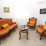Living room with brown leather sofas, two armchairs, and a wooden table.