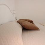 A bed with white headboard and brown pillows.