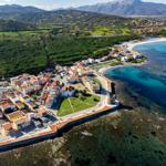 Small coastal village with view of mountains and green landscape.