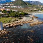 Old tower house by the shore with view of coastal landscape and town.
