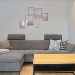 Ein grauer Sofa mit Kissen und einem Holztisch im Wohnzimmer.