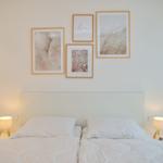 Ein Bett mit weißen Kissen und Decken, zwei Nachttische mit Lampen und Wanddekoration.