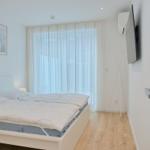 Schlafzimmer mit Bett, TV und Fenster mit Vorhängen.