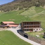 Modernes Holzhaus mit Terrasse, Spielplatz und Garage in grüner Berglandschaft.