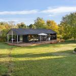 Modern wooden cabin with terrace, garden, and Danish flag.