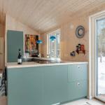 Kitchen with wooden walls and ceiling, blue countertop, and snowy view.