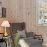 A room with wood wall, armchair, chair, and window.