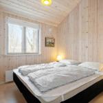 Bedroom with wooden walls, bed, and window with view of trees.