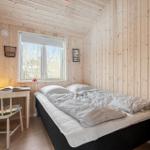 Bedroom with wooden walls, bed, desk, and window.