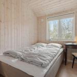 Bedroom with wooden walls, bed, desk, and window.