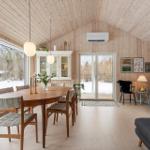 Dining room with wooden ceiling, table and chairs, windows and glass door to outdoor terrace.
