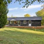 Modern black cabin with wooden terrace and garden. View through large windows.