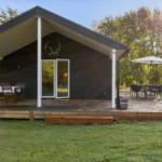 Wooden cabin with deck and garden. Table and chairs under umbrella.