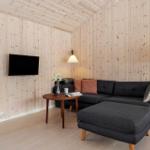 Living room with wooden walls, sofa, coffee table, and TV.