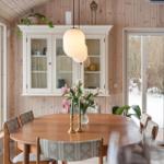 Dining room with wooden table, chairs, and glass doors. Windows show snow.