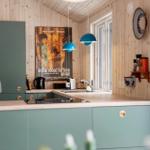 Kitchen with green cabinets, wooden walls, and blue pendant lights.